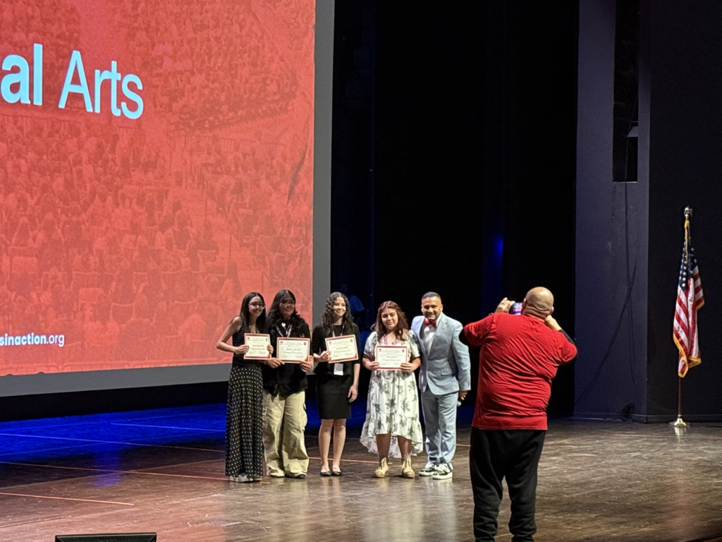 Student standing on stage holding certificates