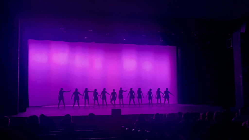 image of girls standing on a stage with a purple background