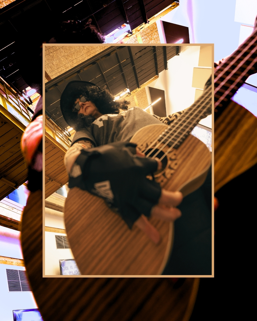 Someone holding a guitar and wearing gloves strums the guitar towards me. 