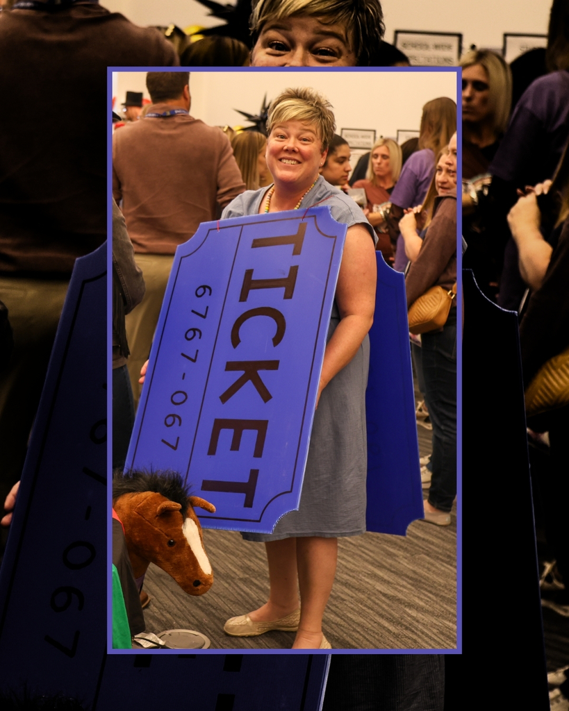 A lady wearing a ticket costume with the numbers 6767-067 on it smiles at the camera