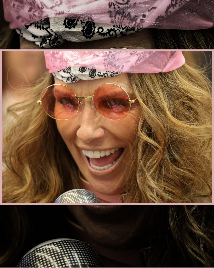 A principal dressed up in a bandanna and glasses holding a fake microphone.