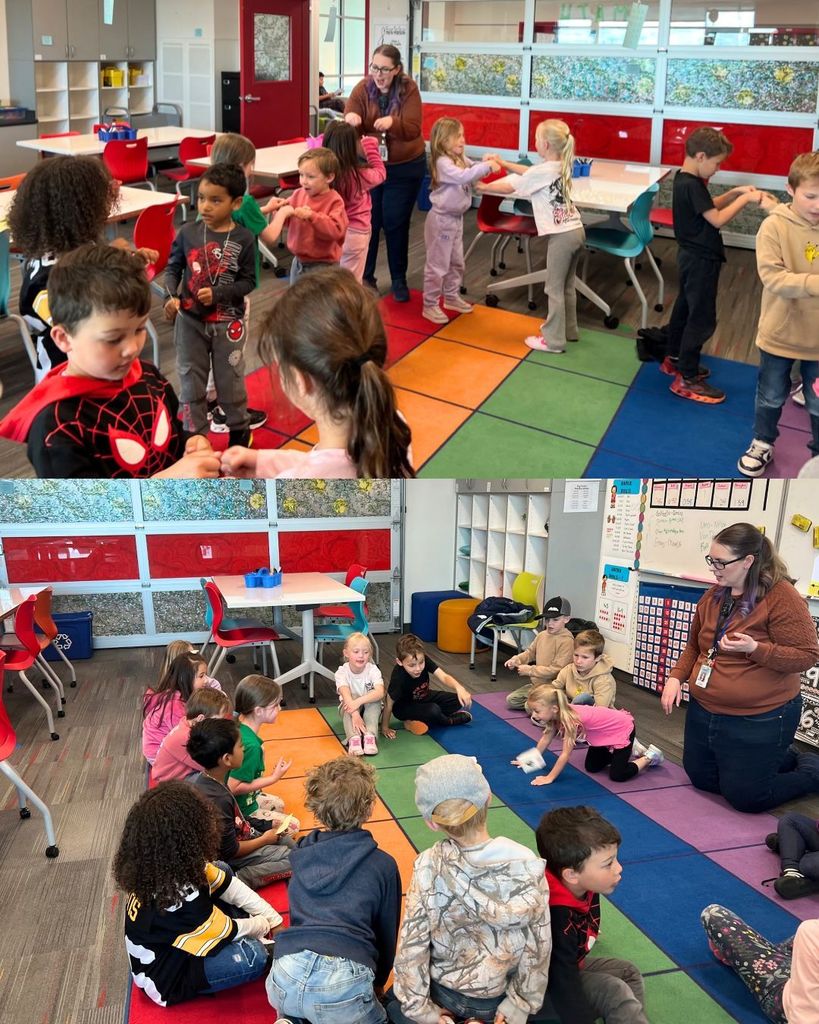 A teacher leads a group of young students gathered on a colorful rug, engaging in a hands-on group activity while others stand and interact nearby in a bright classroom.