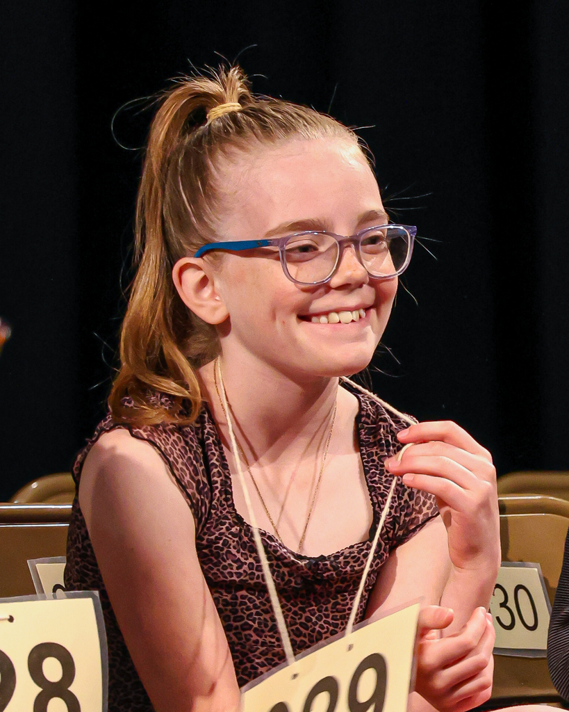A student sitting on a chair smiles happily. 