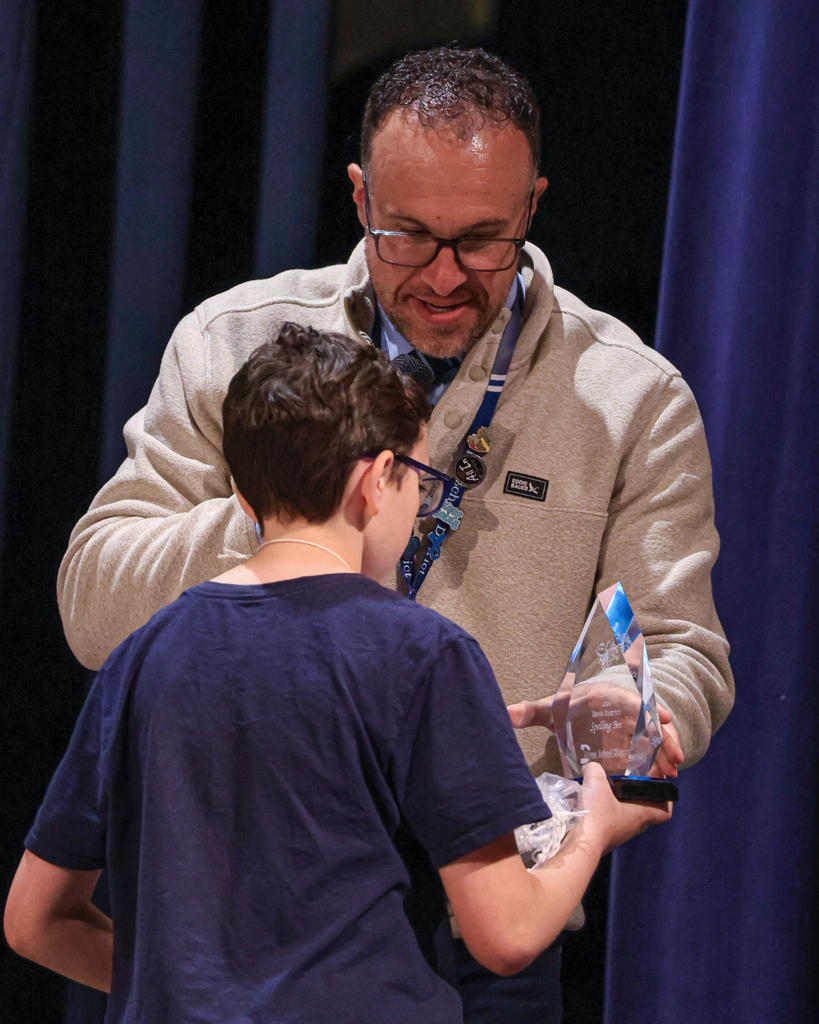 An adult handing a student a crystal trophy. 