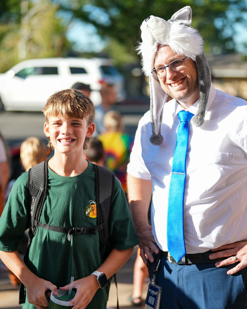 A principal wearing a wolf hat poses for a picture with a student. 