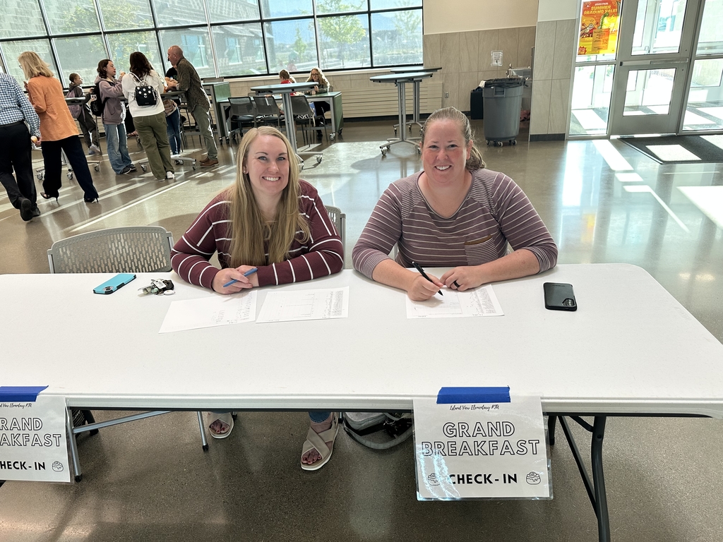 two ladies behind a table with grand breakfast sign on the table