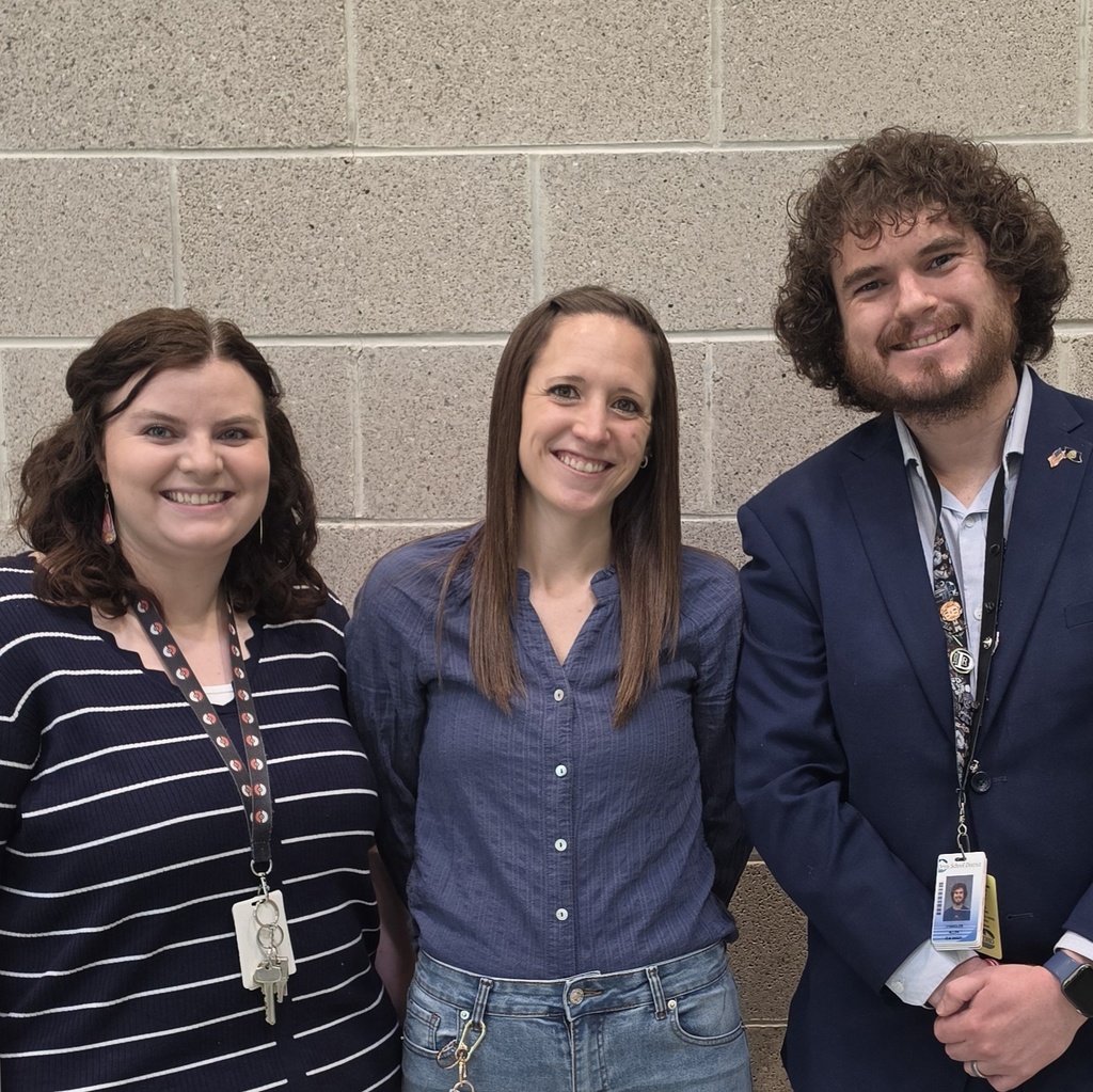 Three Bountiful Elementary 4th grade teachers smile together in front of a school wall after the fourth grade Utah history program.