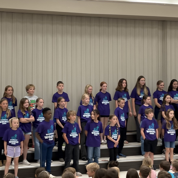 The Windridge student choir can be seen on the stage preparing to sing for the rest of the school.
