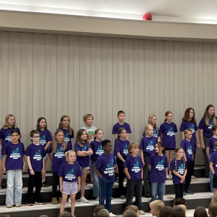 The Windridge student choir can be seen on the stage preparing to sing for the rest of the school.