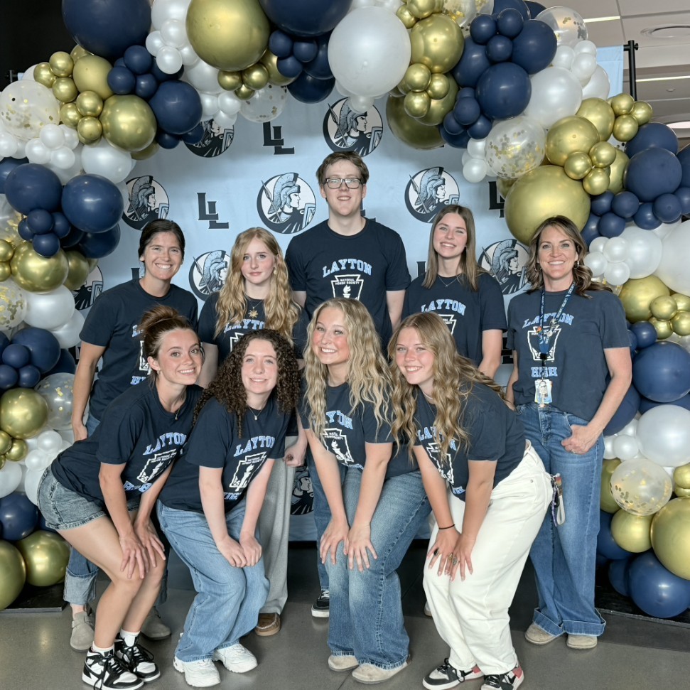 National honors society members and advisors standing under a balloon arch