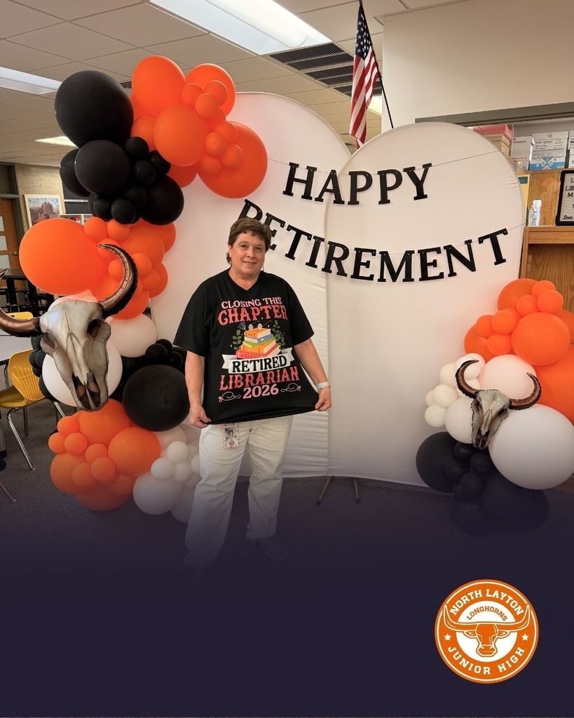 Ms Combe, the librarian, standing in front of a Happy Retirement sign in the library of North Layton Jr. High