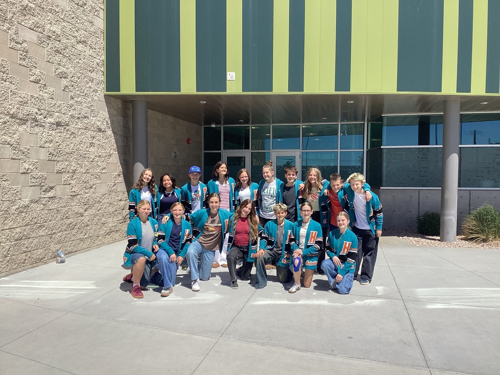 group of students in teal student government jackets in front of a school