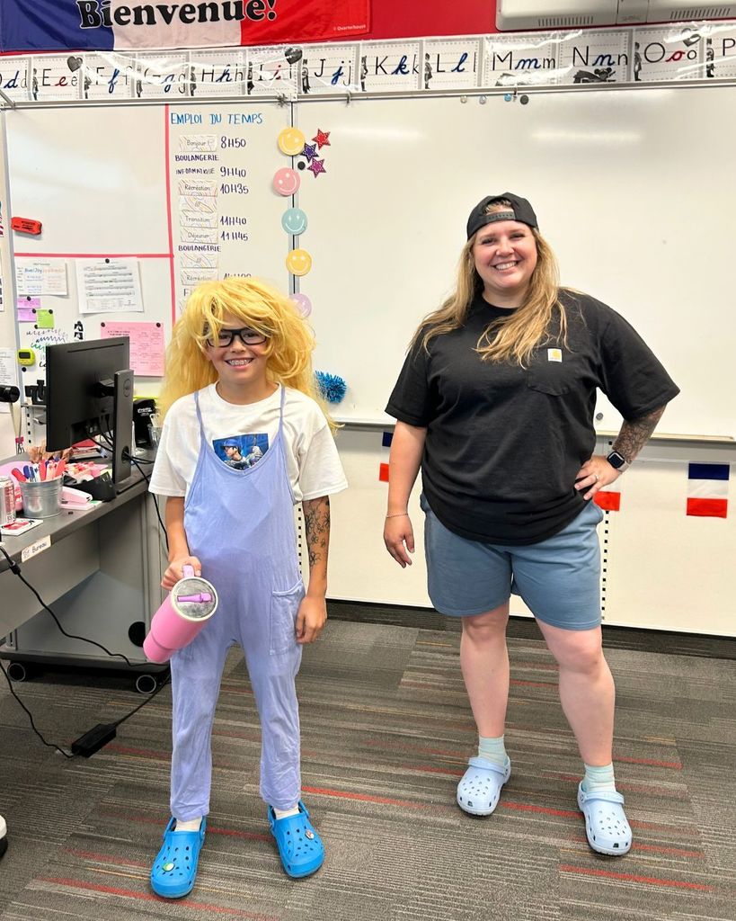 A student dressed up as Mrs. Joy while Mrs. Joy dressed up as the student for a fun classroom spirit day. Both are smiling and posing in matching casual outfits and Crocs.