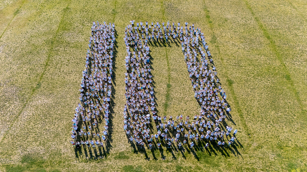 students lined up in the shape of number 100 on the field