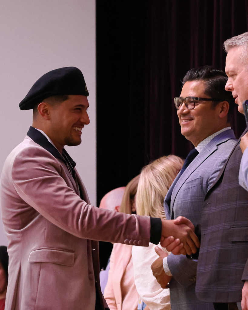 A student shakes the hand of the superintendent.