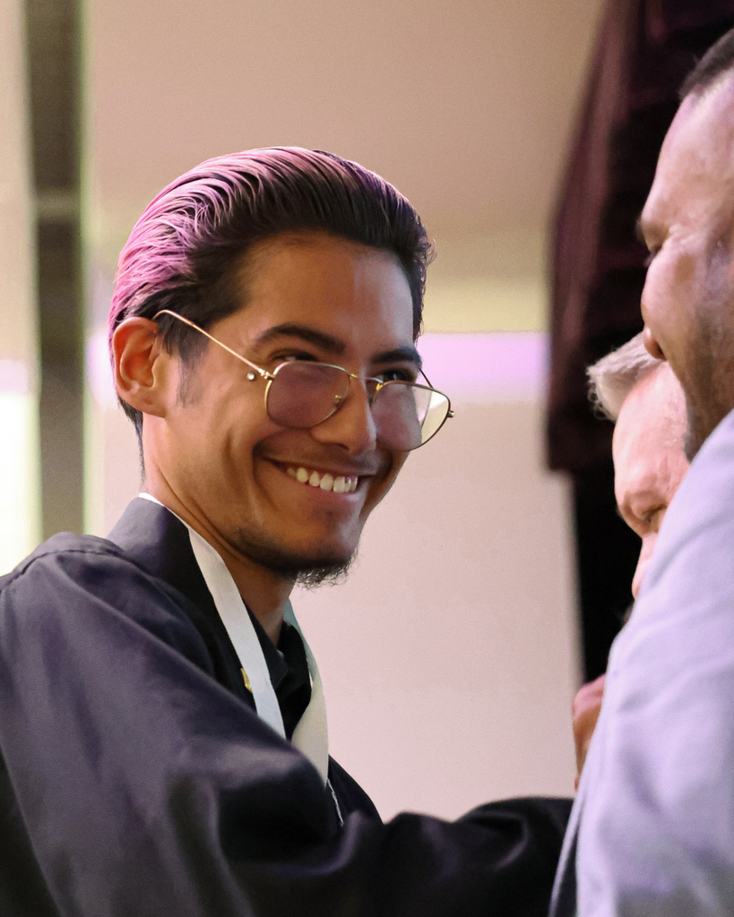 A student smiles as they look over their glasses.