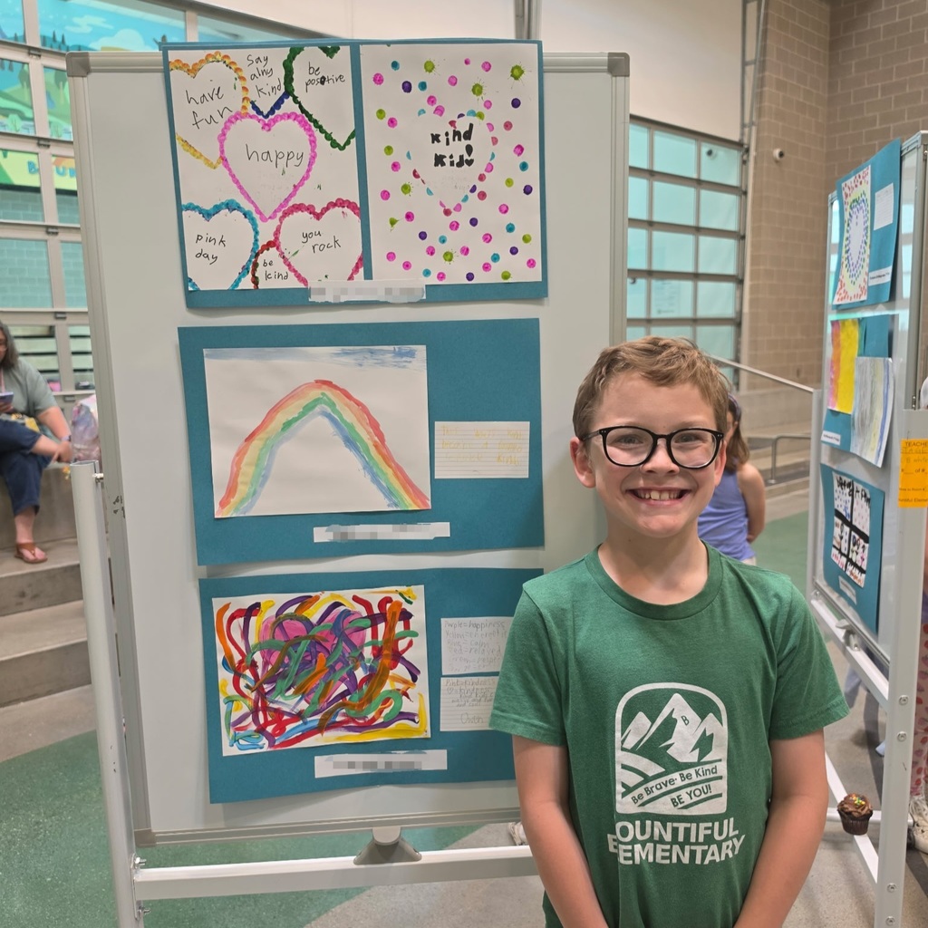 Bountiful Elementary student stands beside kindness-themed student artwork