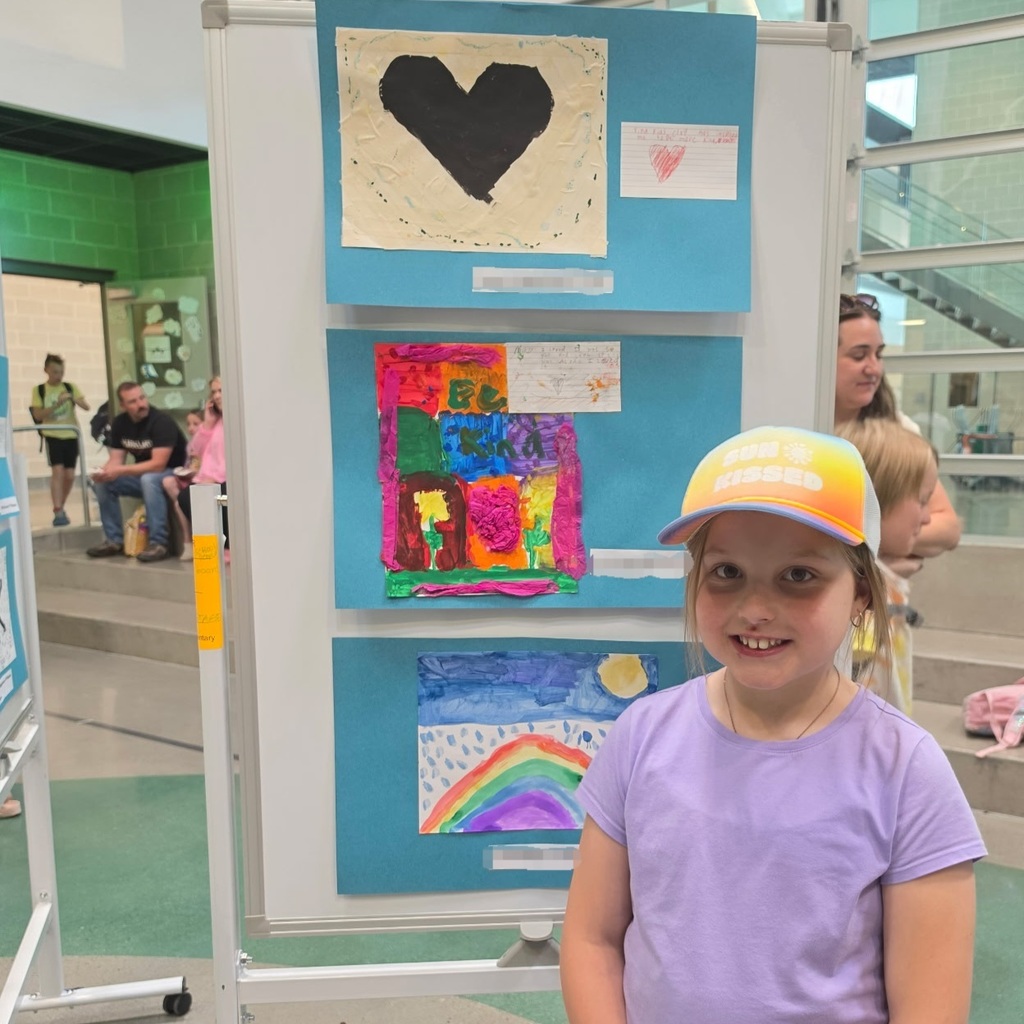 Bountiful Elementary student stands beside kindness-themed student artwork