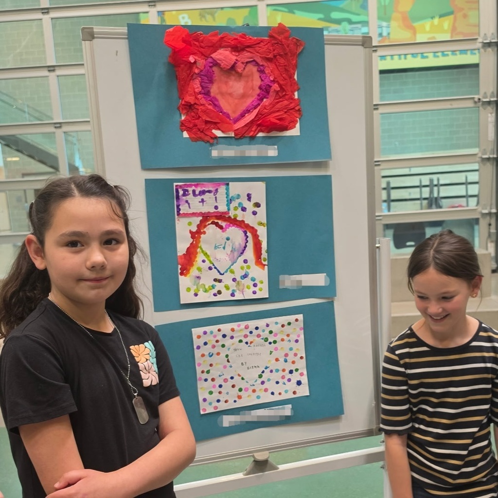 Bountiful Elementary students stand beside kindness-themed student artwork
