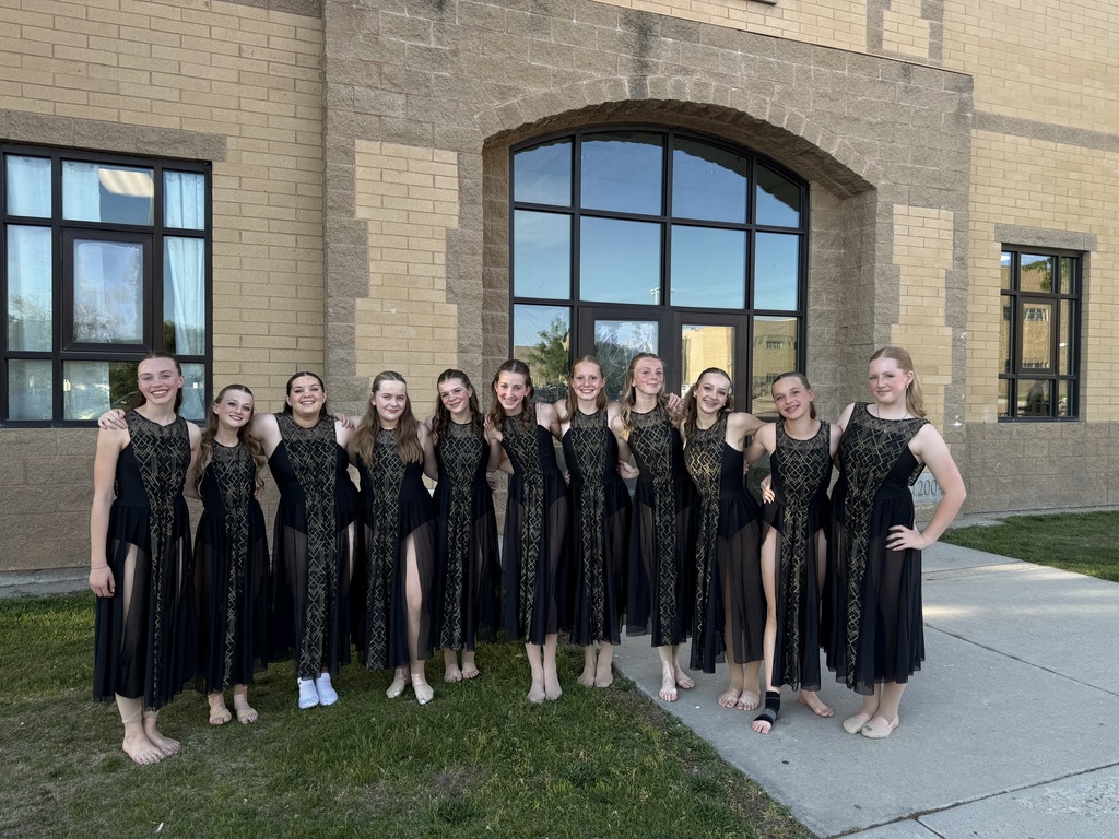 image of students standing in front of a building together in dance dresses. 