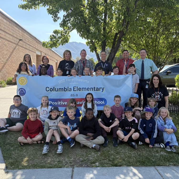 Columbia students and staff posing for picture with a PBIS banner  