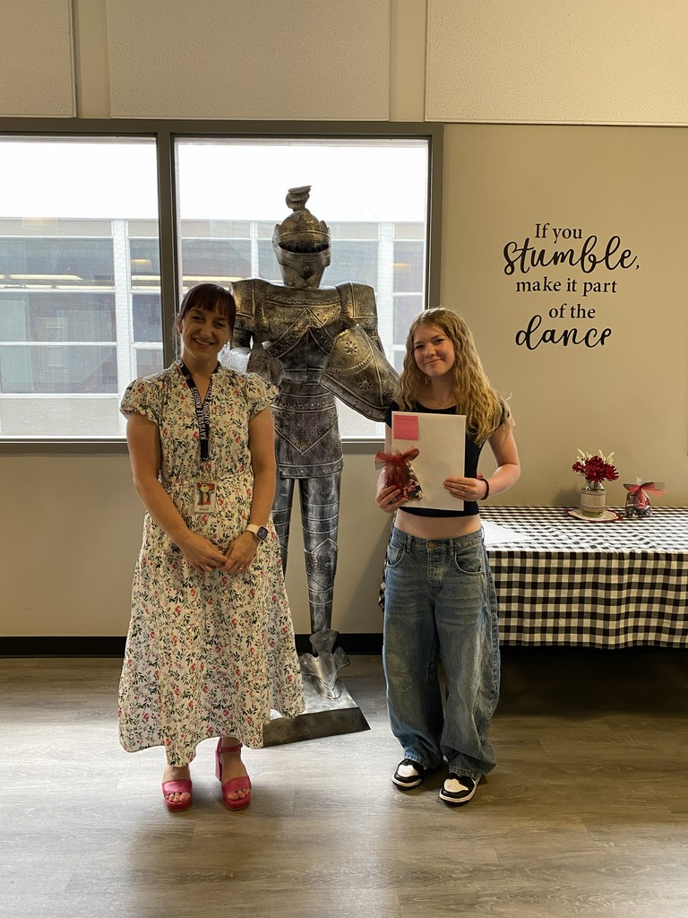image of student and school staff standing next to a knight statue