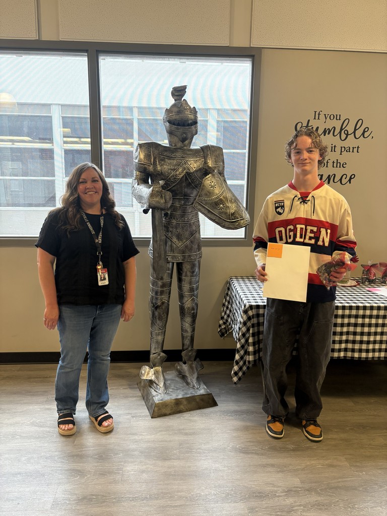 image of a student and school staff standing next to a knight statue