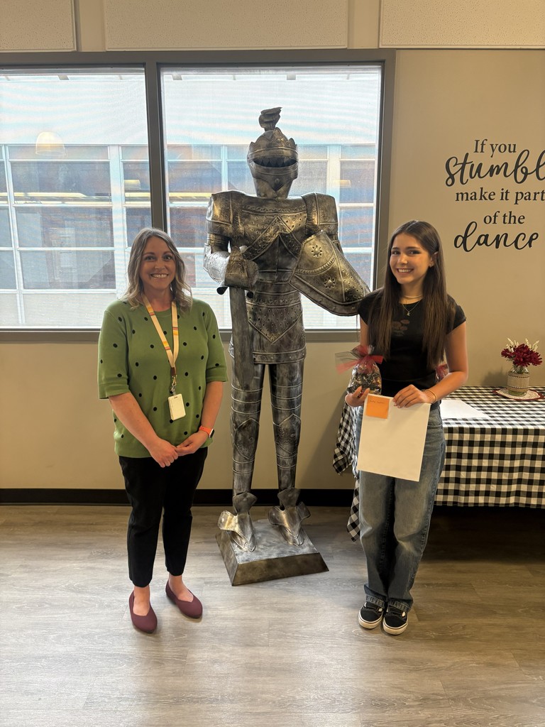 image of student and school staff standing next to a knight statue