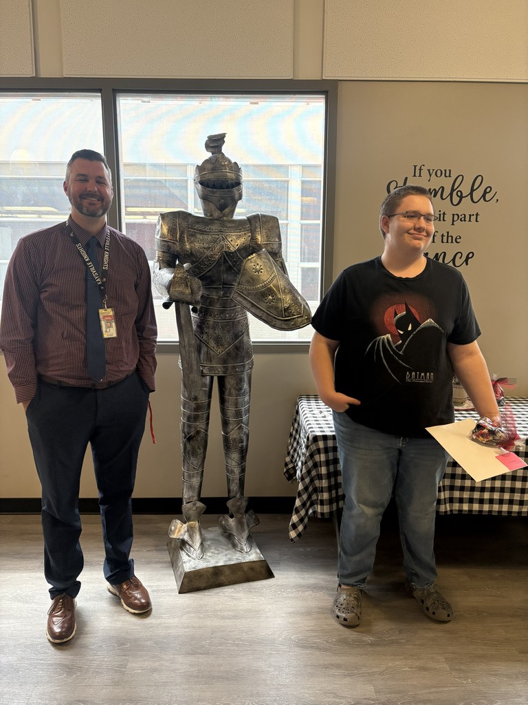 image of student and school staff standing next to a knight statue