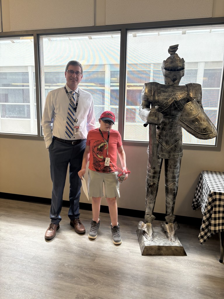 image of student and school staff standing next to a knight statue