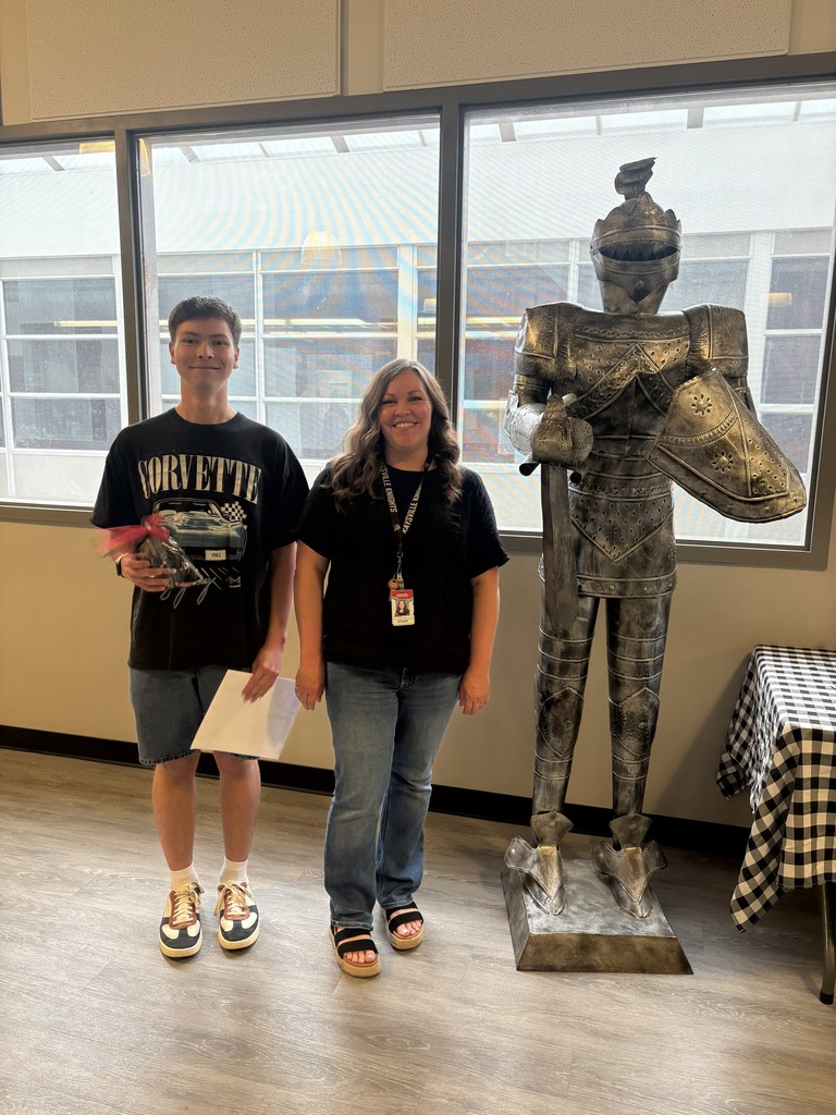 image of a student and school staff standing next to a knight statue