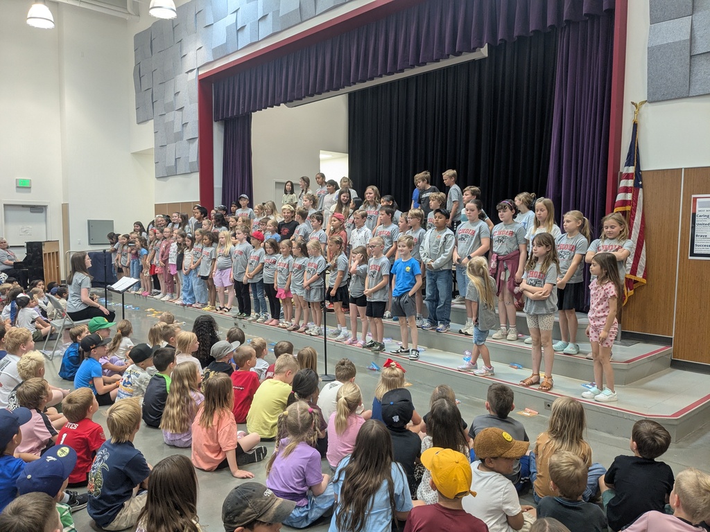 Choir students performing on stage at a school-wide assembly.