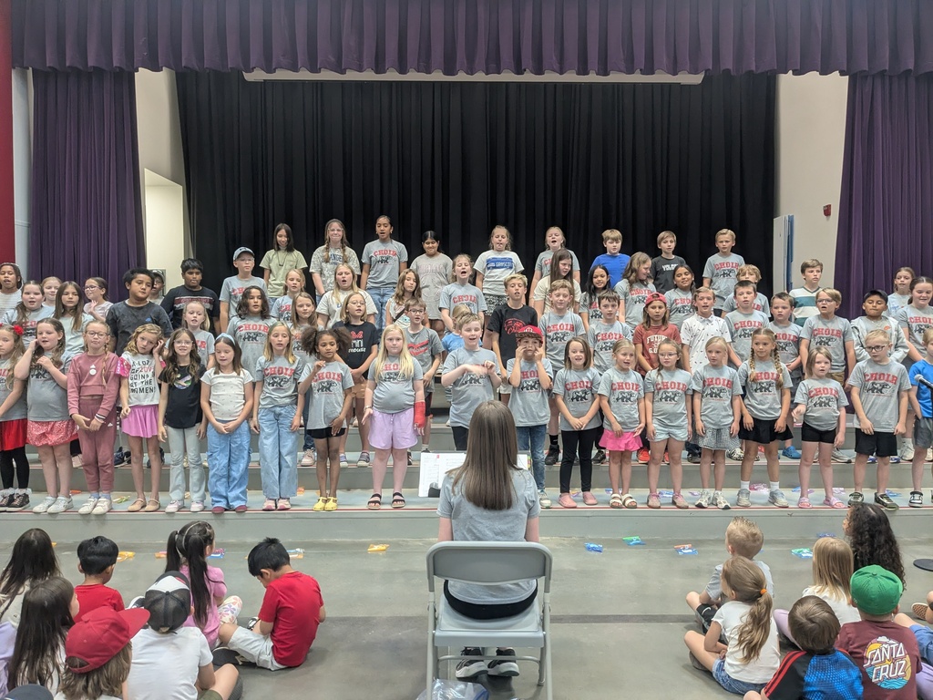 Choir students performing on stage at a school-wide assembly.