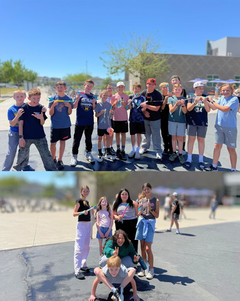 Groups of 6th grade students stand outside on a sunny day holding handmade rockets before launch day. Students smile and pose together on the blacktop near the school building during the STEM rocket activity.