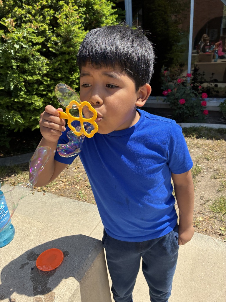 student wearing a blue shirt outside blowing bubbles