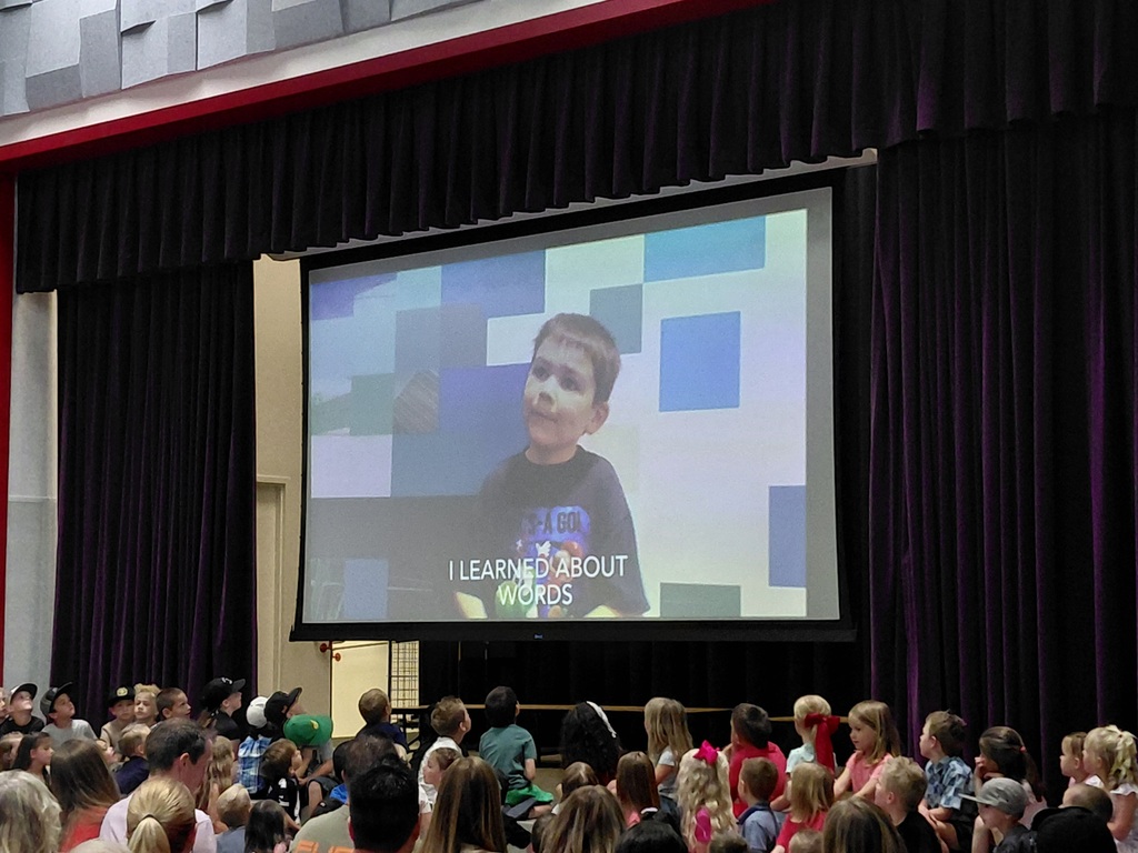 Kindergarten performing their end of year program on the stage in front of parents. 