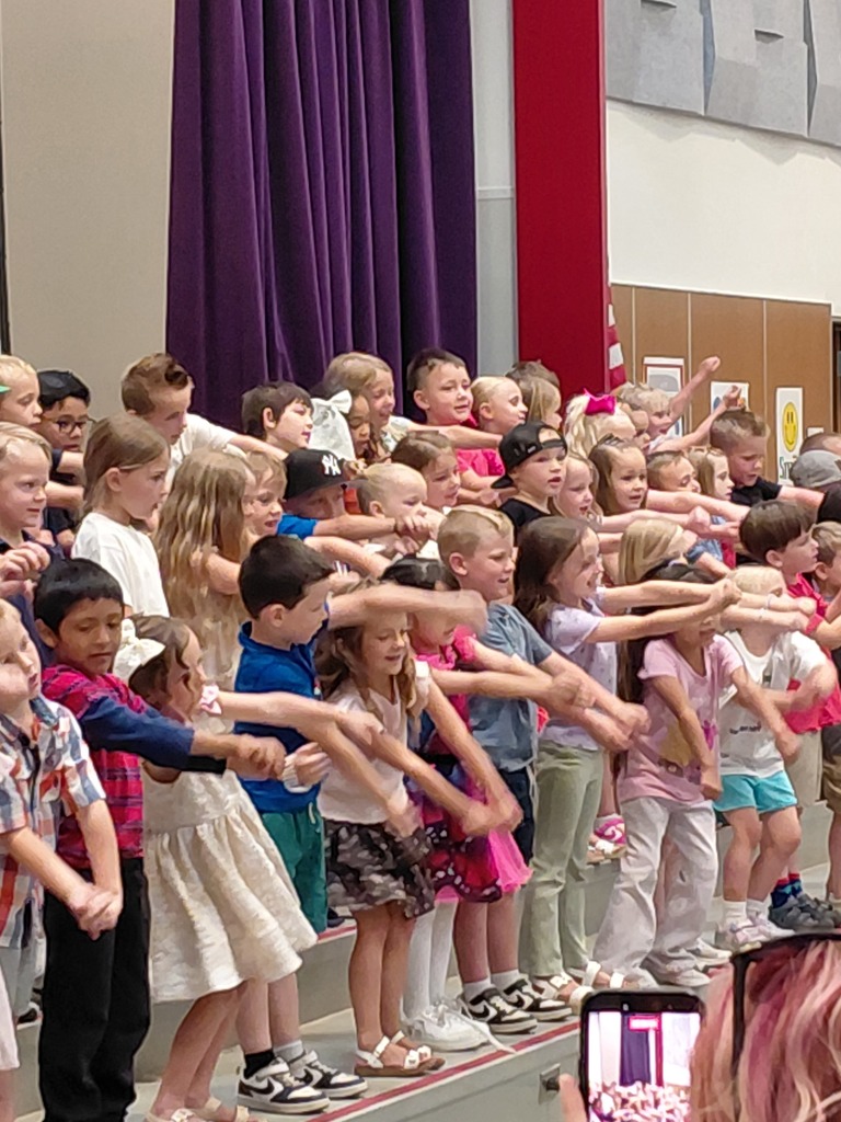 Kindergarten performing their end of year program on the stage in front of parents. 