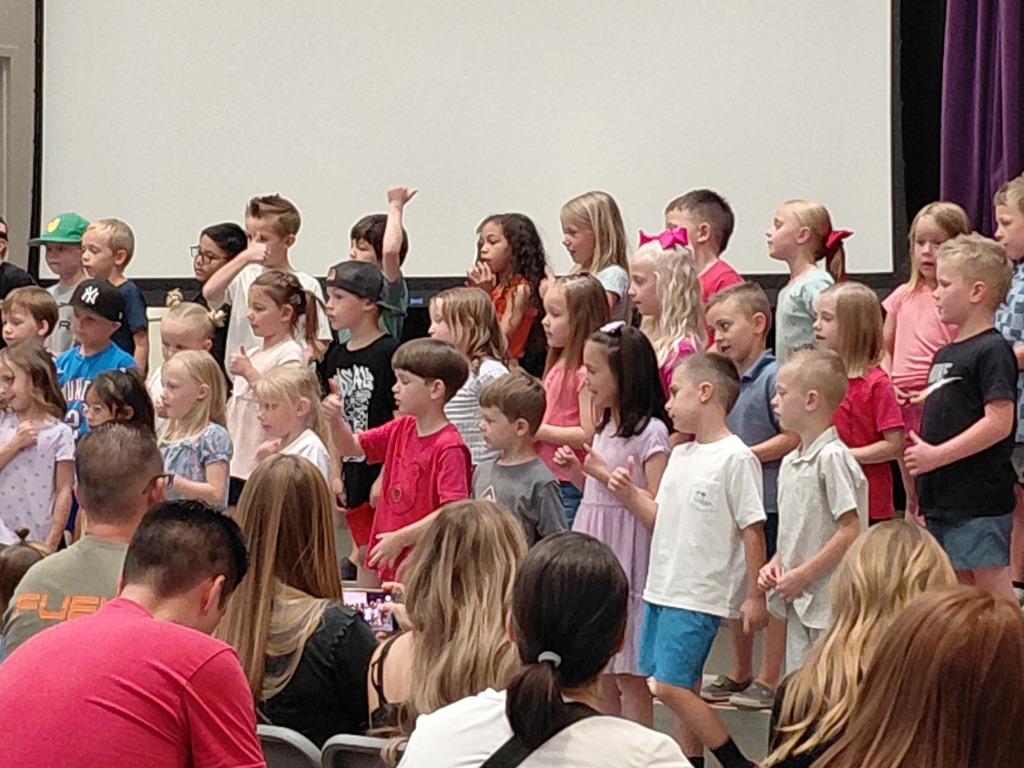 Kindergarten performing their end of year program on the stage in front of parents. 