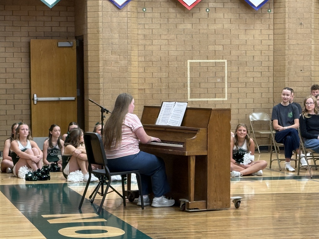 Student playing the piano and singing for the assembly. 