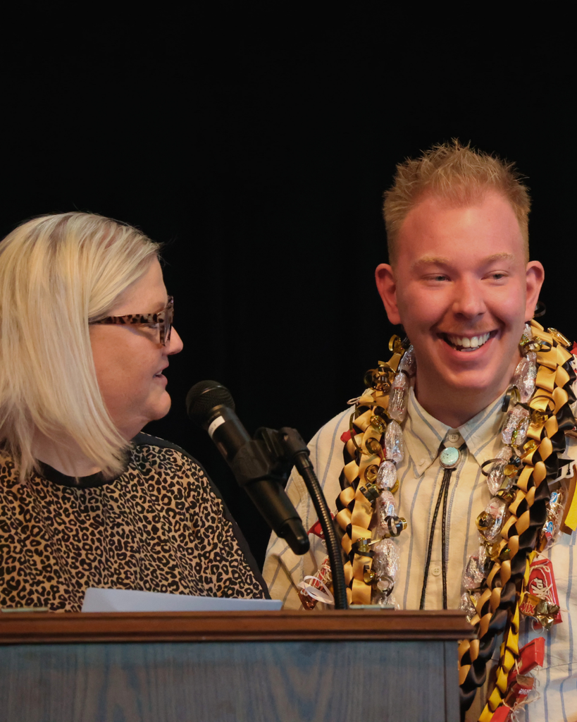 A Vista Education Campus graduate wearing leis smiles at the crowd. 