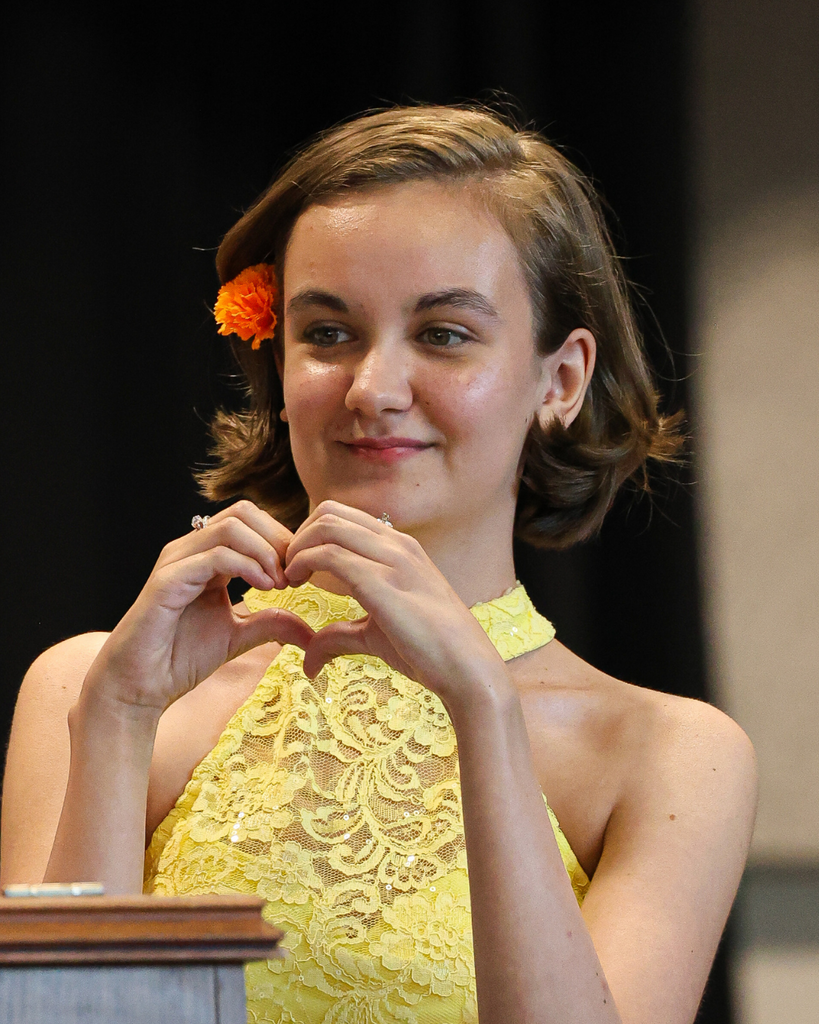 A Vista Education Campus graduate makes a heart sign to the crowd.