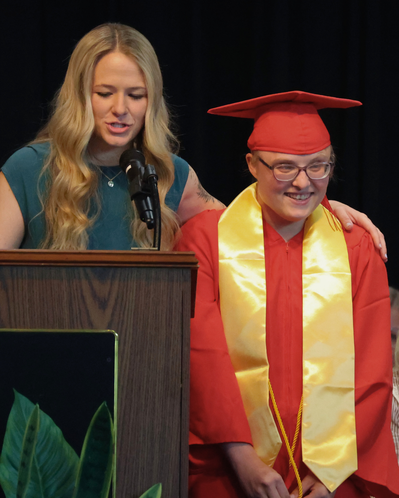A Vista Education Campus graduate smiles next to his teacher. 