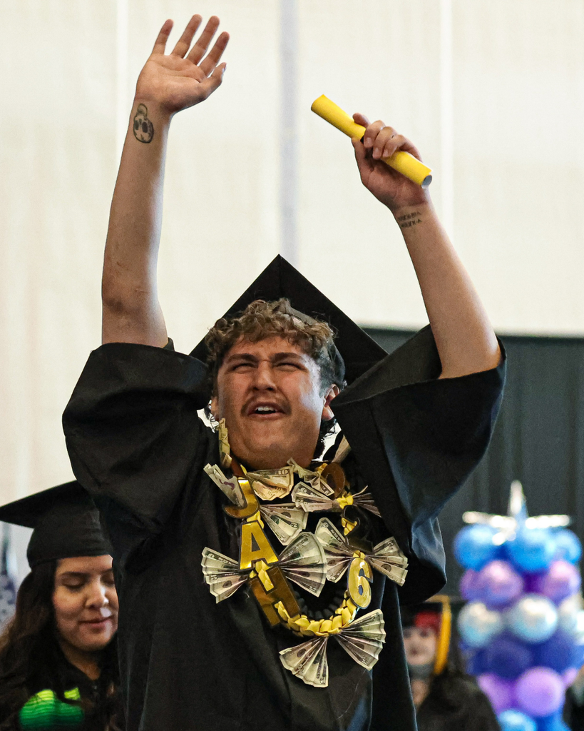 Davis Adult Education graduate celebrates with his arms raised.
