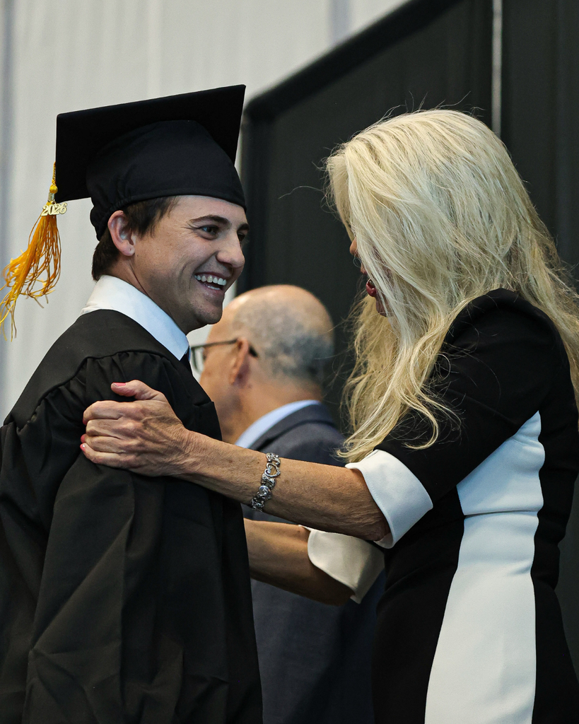Davis Adult Education graduate smiles and hugs a mentor.