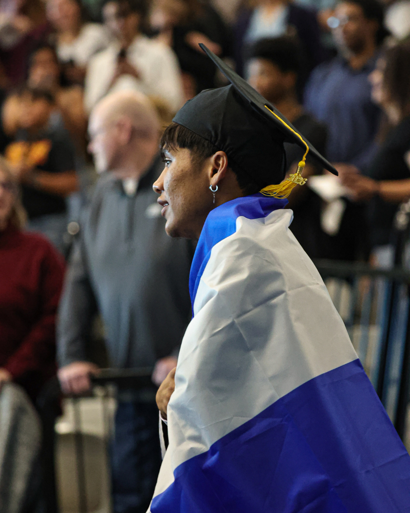 Davis Adult Education graduate walks as he is wrapped in his country's flag. 