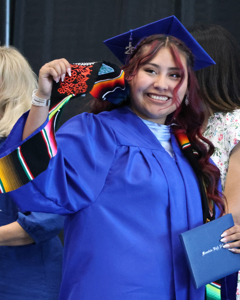 A Mountain High graduate smiling and holding up her diploma cover. 