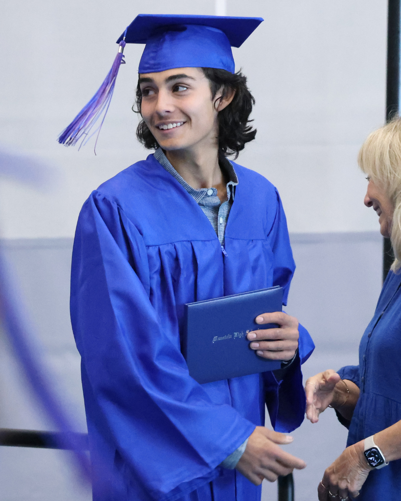 A Mountain High graduate holding their diploma smiling. 