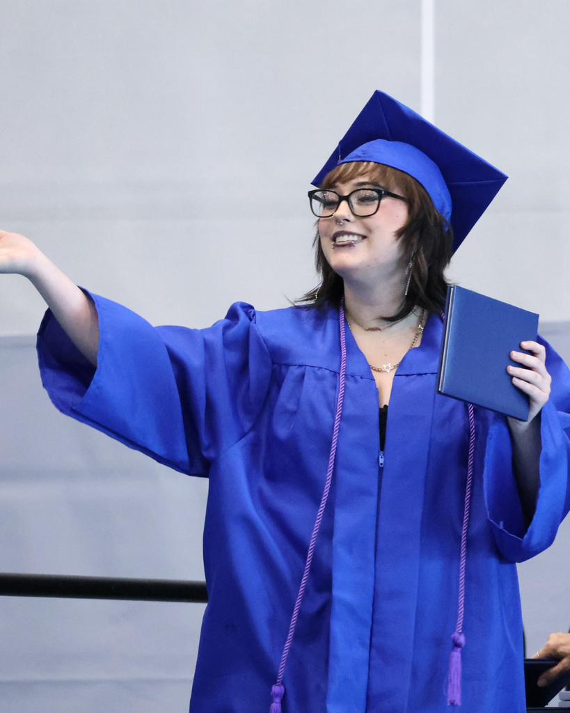 A Mountain High graduate smiling and waving to the right. 