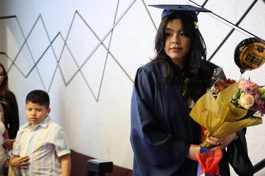 A Davis Connect graduate holding flowers with a "grad" balloon.