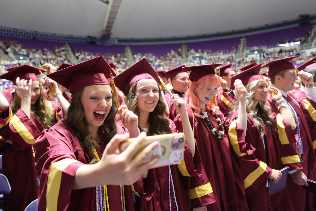 Viewmont High Graduates hold up their phones as they turn their tassels to the left. 